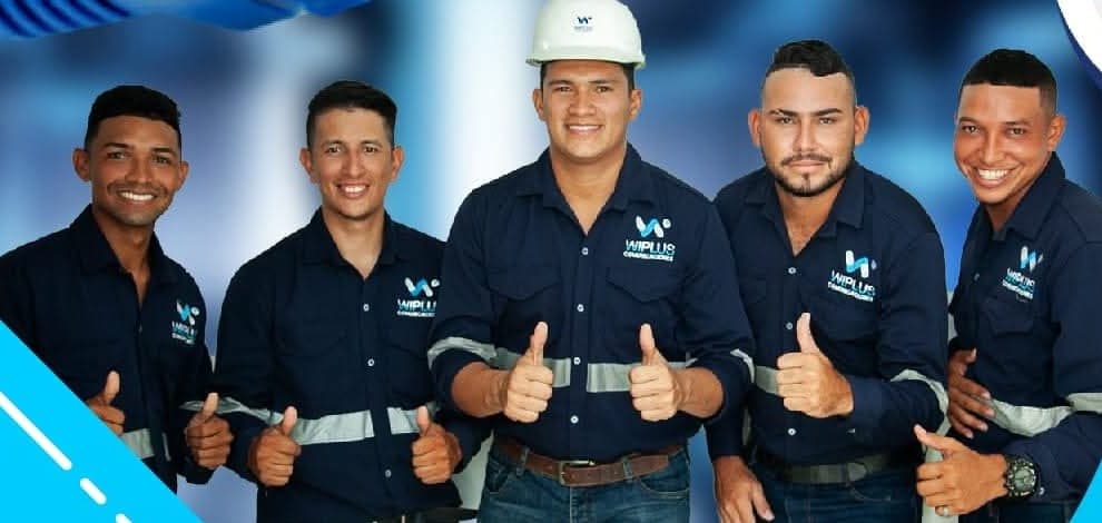 Equipo técnico de WIPLUS Comunicaciones: cinco técnicos con el uniforme azul de la empresa, uno de ellos con casco, haciendo el gesto de aprobación